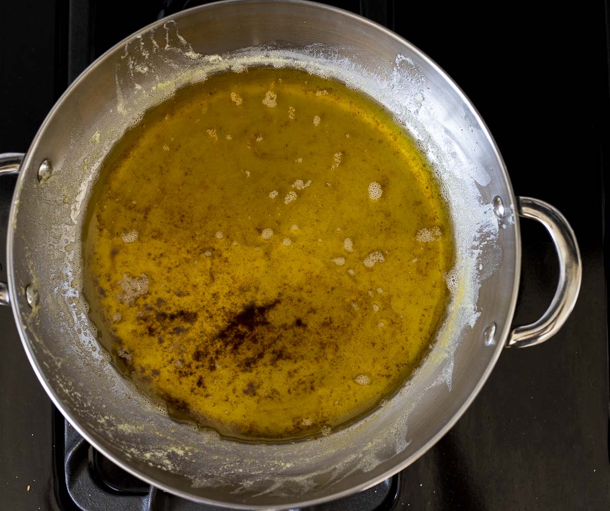 melted butter in a skillet with browned pieces at the bottom