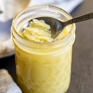 a spoon scraping solid ghee out of a jar