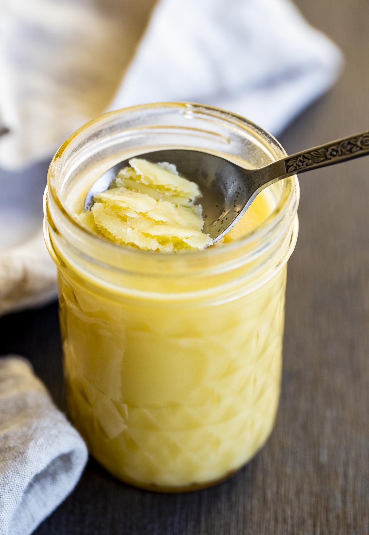 a spoon scraping solid ghee out of a jar