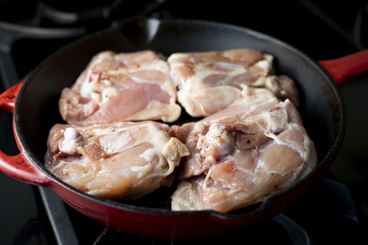raw chicken cooking in a skillet