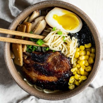 Overhead view of shio ramen in a bowl with menma, braised pork and a marinated egg.