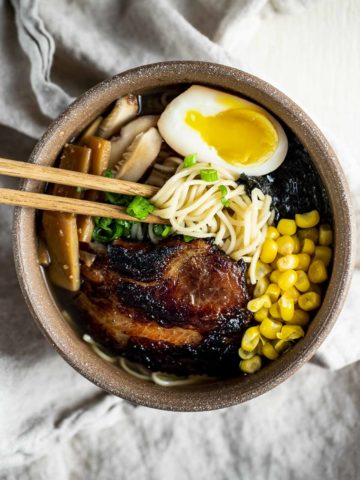 Overhead view of shio ramen in a bowl with menma, braised pork and a marinated egg.