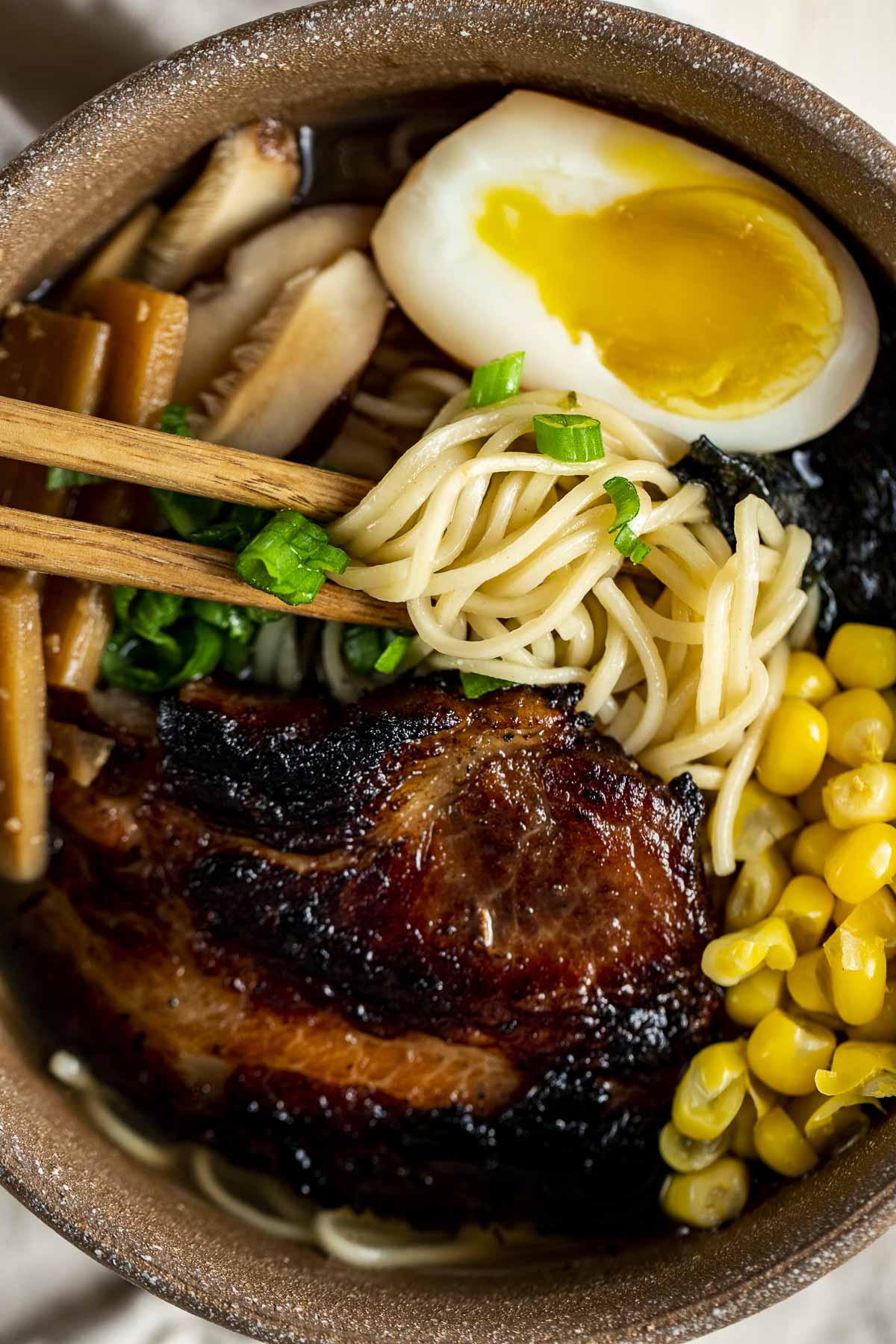 Close up view of shio ramen in a bowl with chopsticks grabbing some noodles.