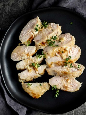 Overhead view of sliced sous vide chicken breasts on a black plate.