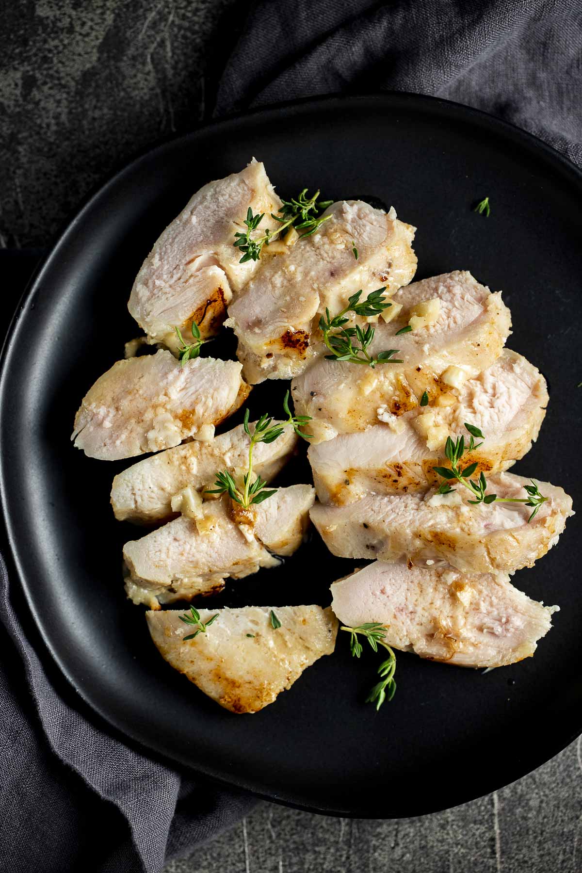 Overhead view of sliced sous vide chicken breasts on a black plate.