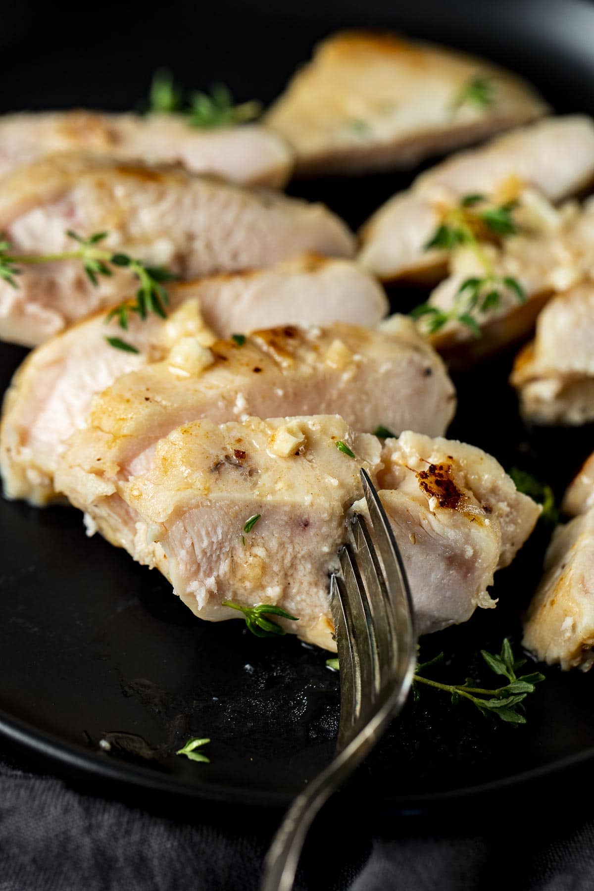 Close up view of chicken breast slices on a plate with a fork.