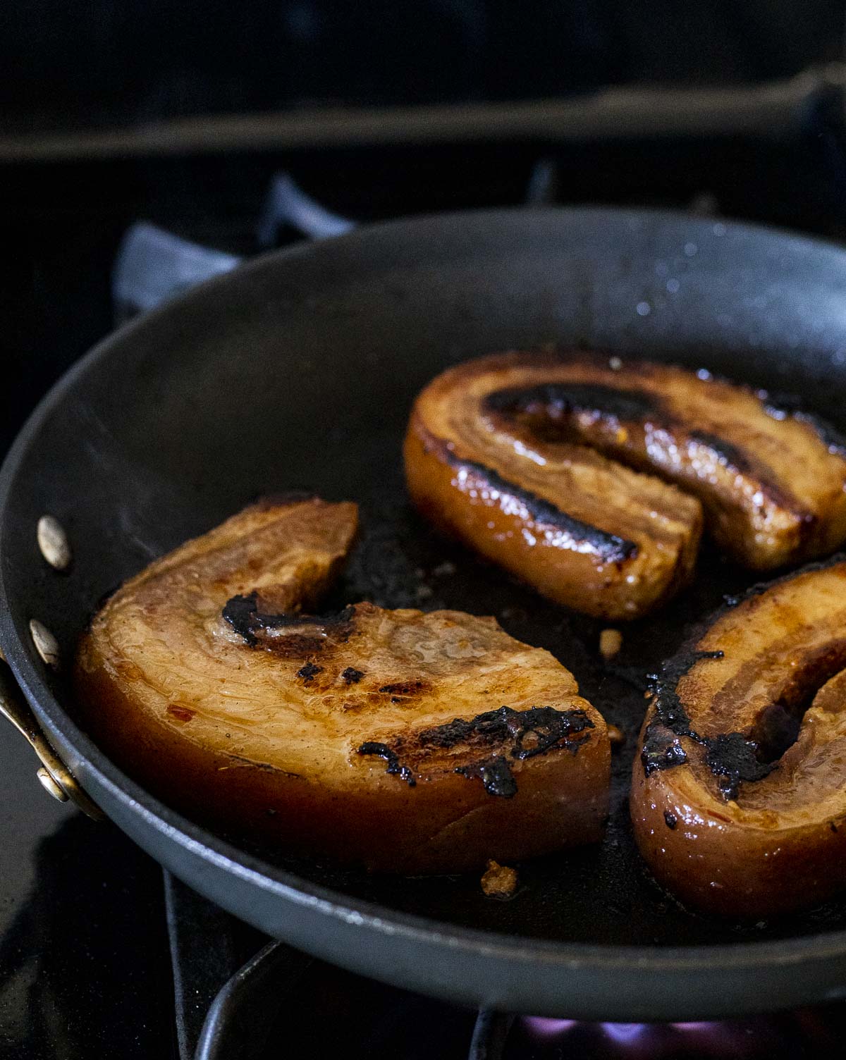 Pieces of sous vide pork belly being browned in a skillet.