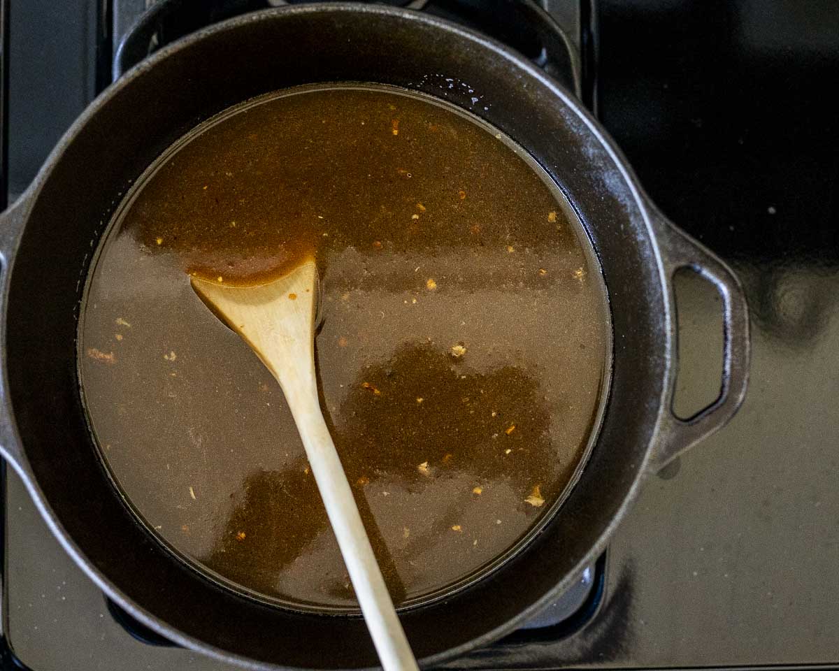 brown broth in a pot with a wooden spoon