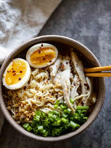 a bowl of ramen with noodles, eggs, chicken and green onions