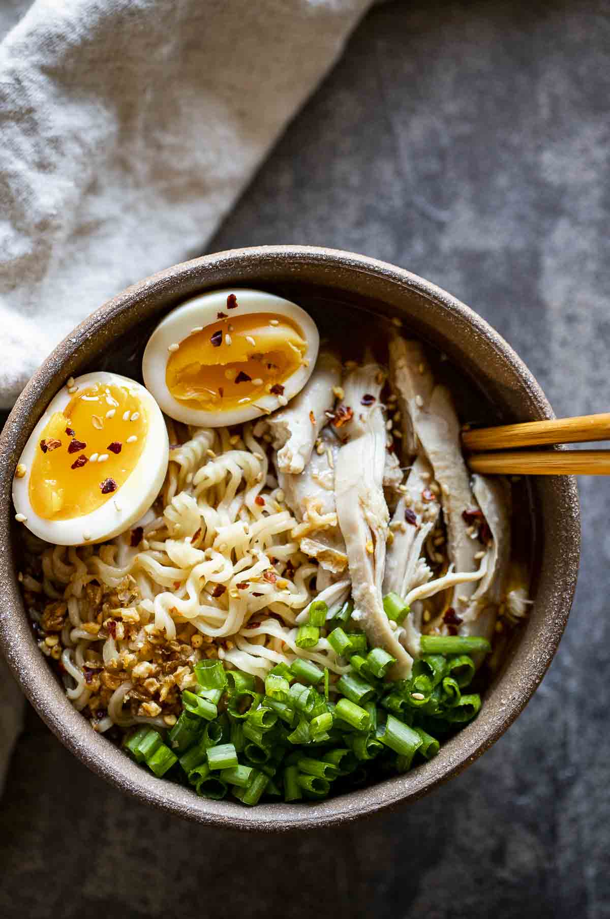a bowl of ramen with noodles, eggs, chicken and green onions