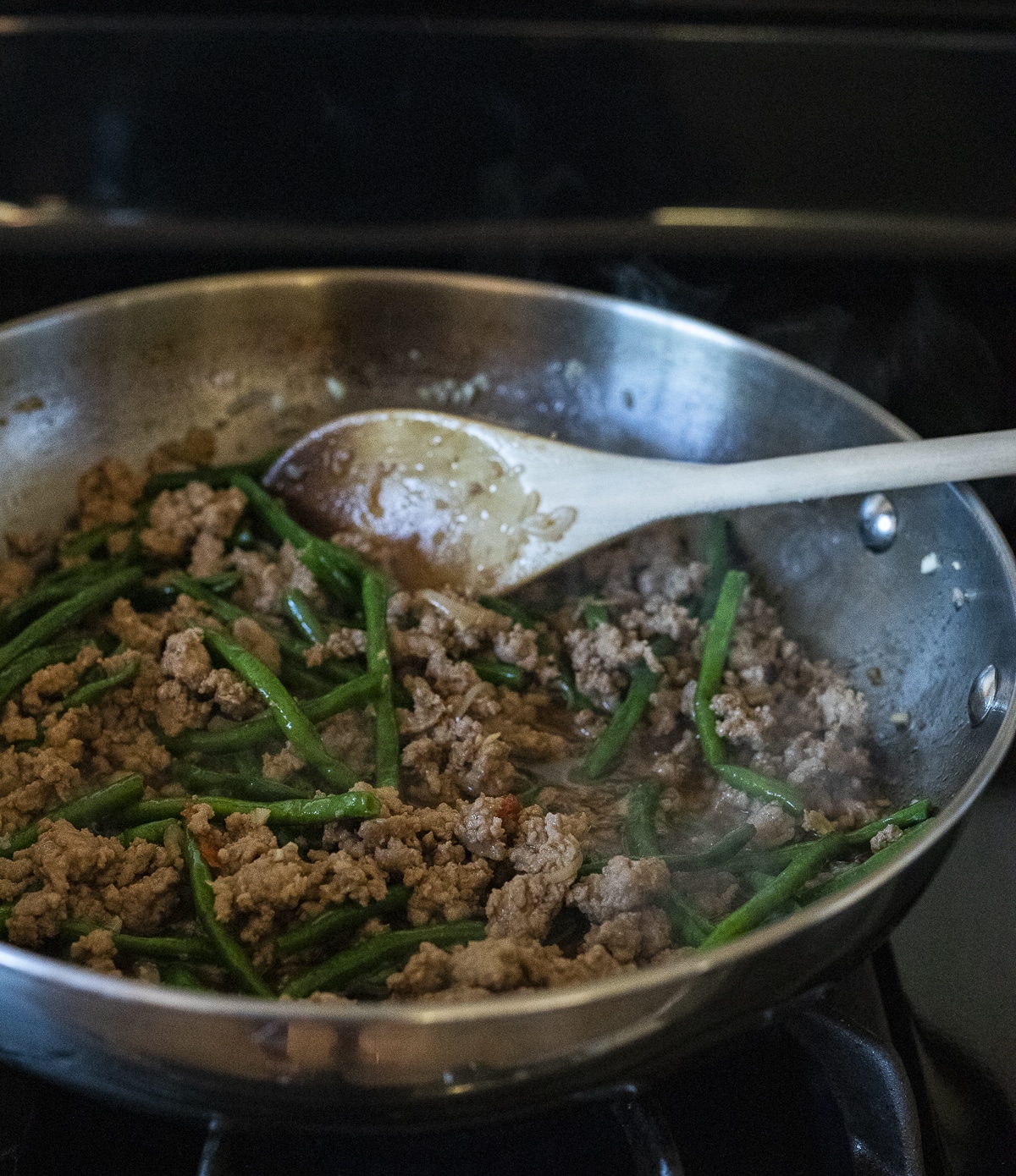 Cooked ground pork and long beans in a wok.