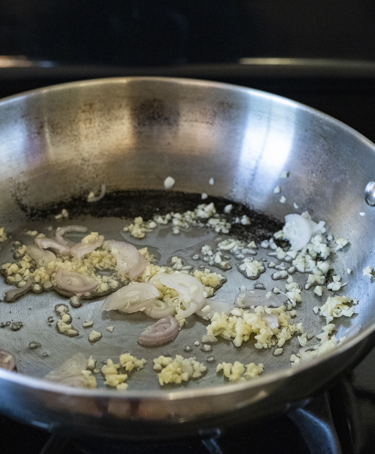 Minced garlic and chopped shallot being cooked in a wok.