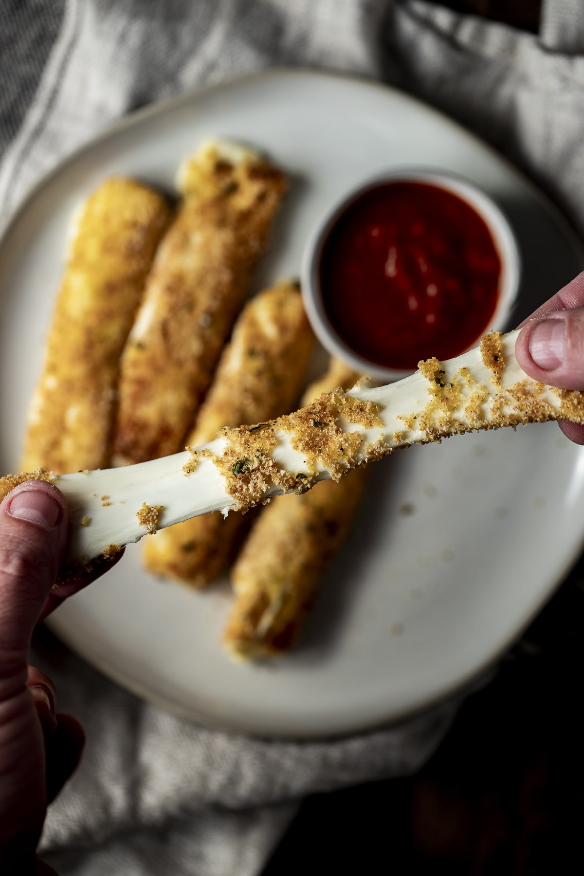 Close up view of a mozzarella stick being pulled apart to expose the stretchy cheese.