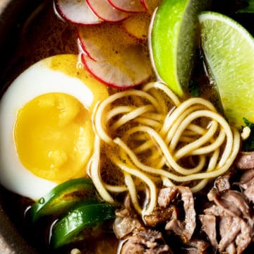 Close up overhead view of birria ramen in a bowl with a ramen egg on top.