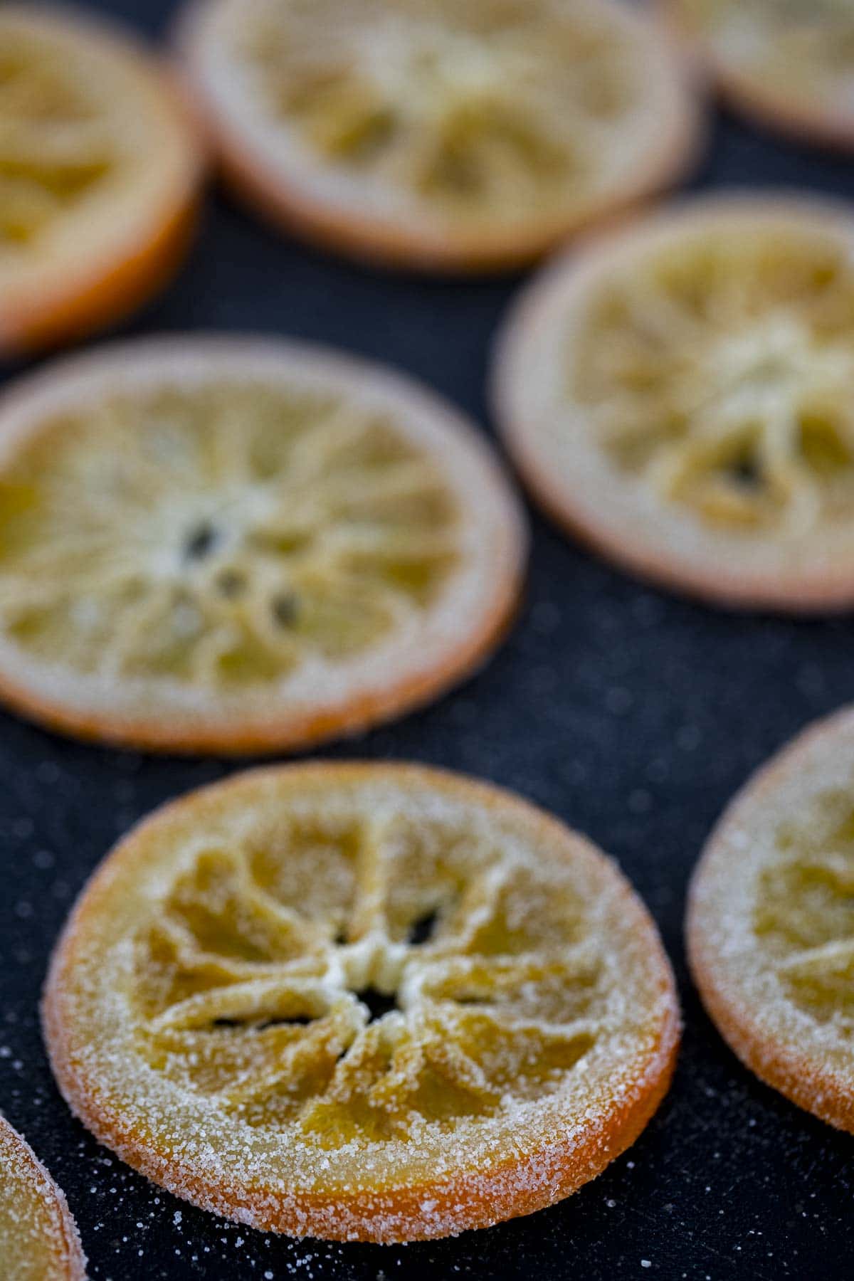 Orange slices coated in sugar and laying flat to dry.