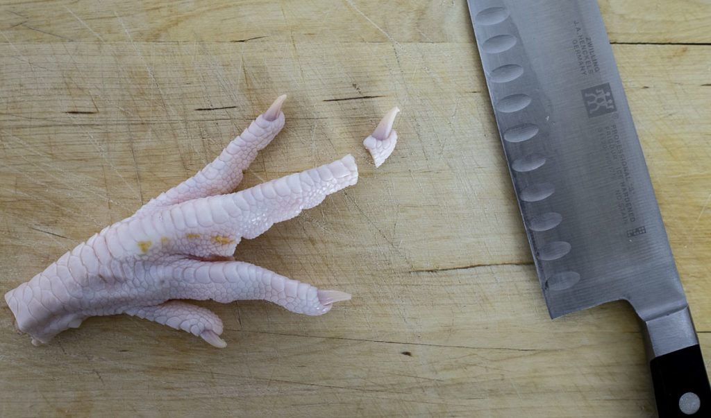 chicken foot with the nail cut off and a knife on the baord