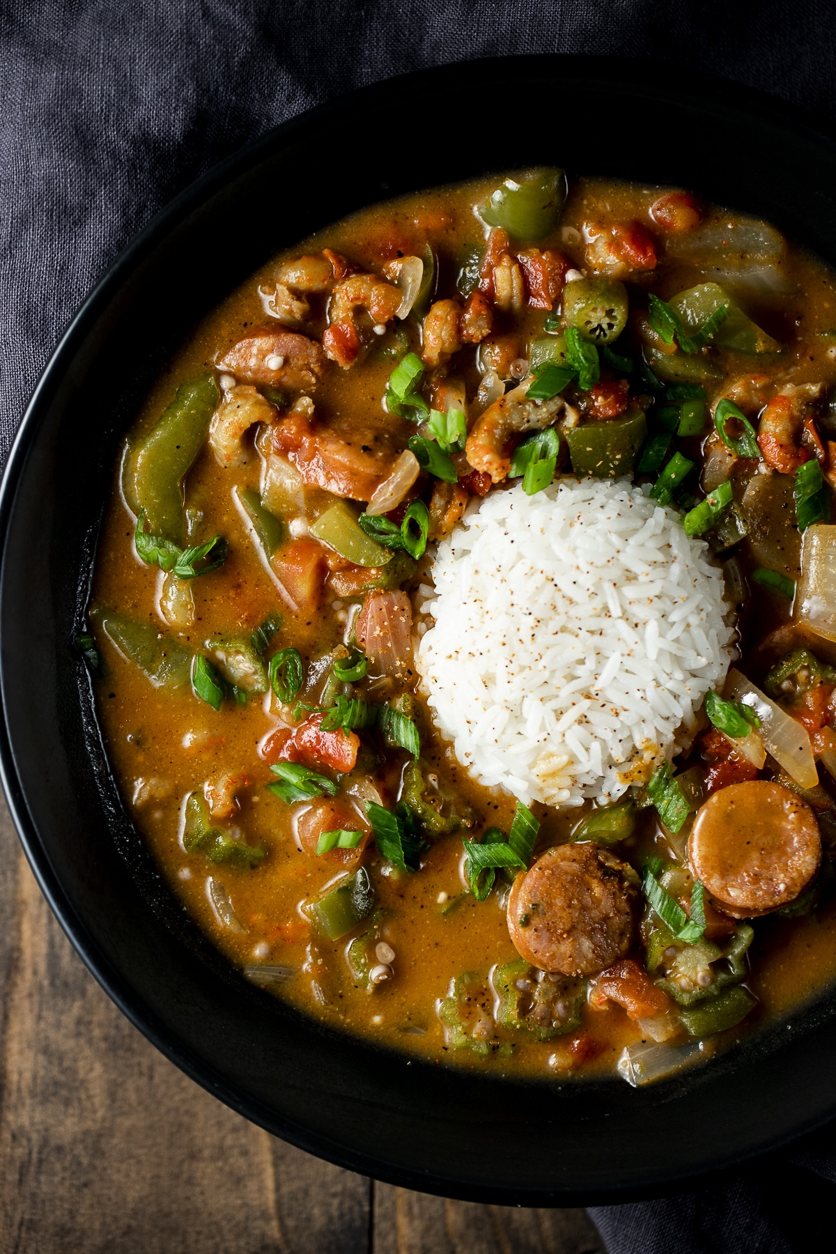 Crawfish gumbo served over rice in a black bowl.