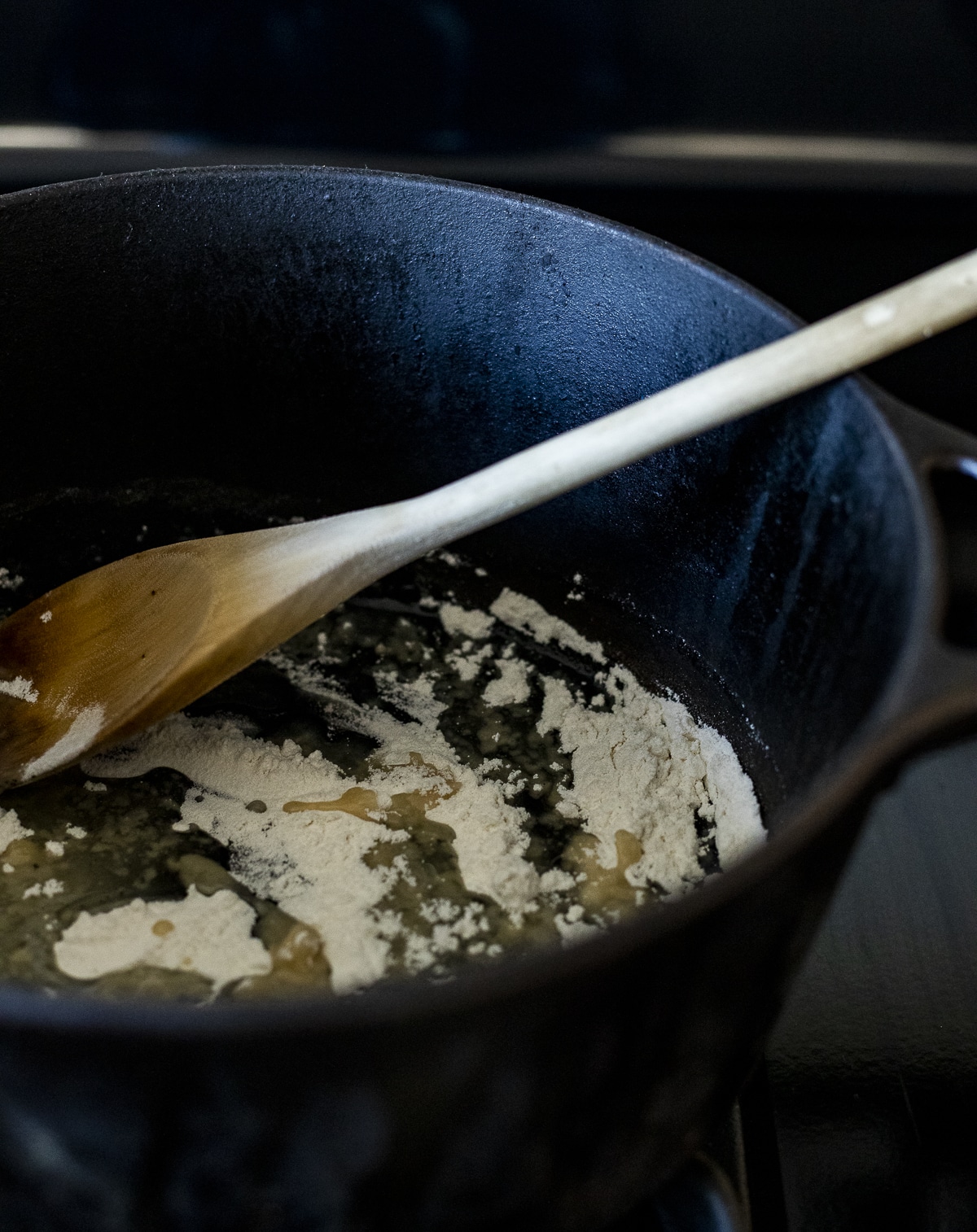 Roux being stirred together with a wooden spoon in a pot.