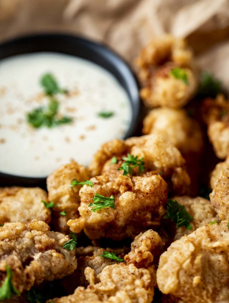 close up piece of fried alligator with white sauce in the background