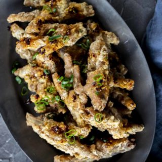 a plate of crispy chicken feet garnished with green onions