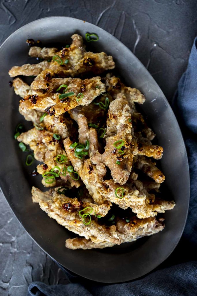 a plate of crispy chicken feet garnished with green onions
