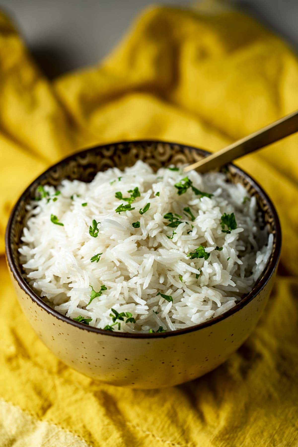A bowl of fluffy basmati rice on a yellow cloth.