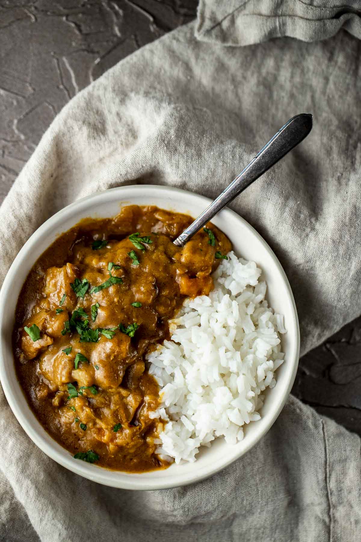 chicken and vegetables in orange curry sauce with rice in a bowl