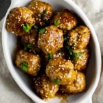 a bowl of meatballs with an orange glaze and sesame seeds