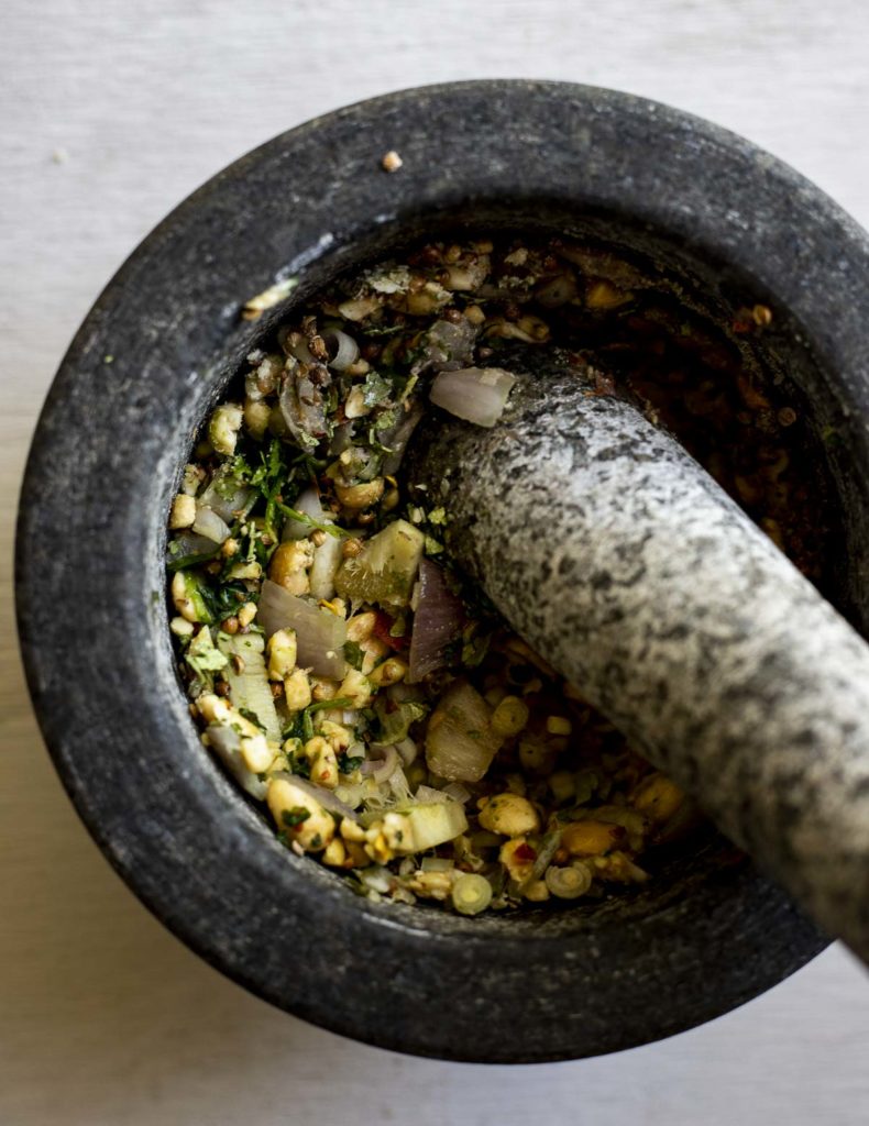 ingredients being smashed with a pestle in a mortar