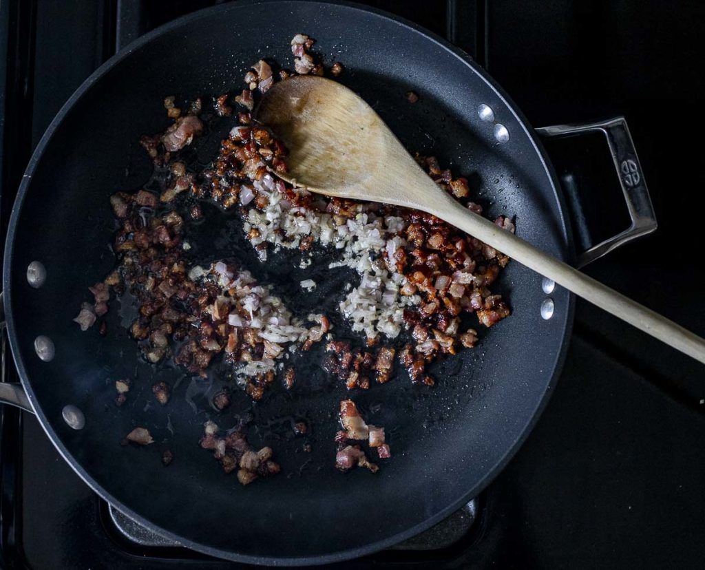 pancetta and diced shallots frying in a skillet