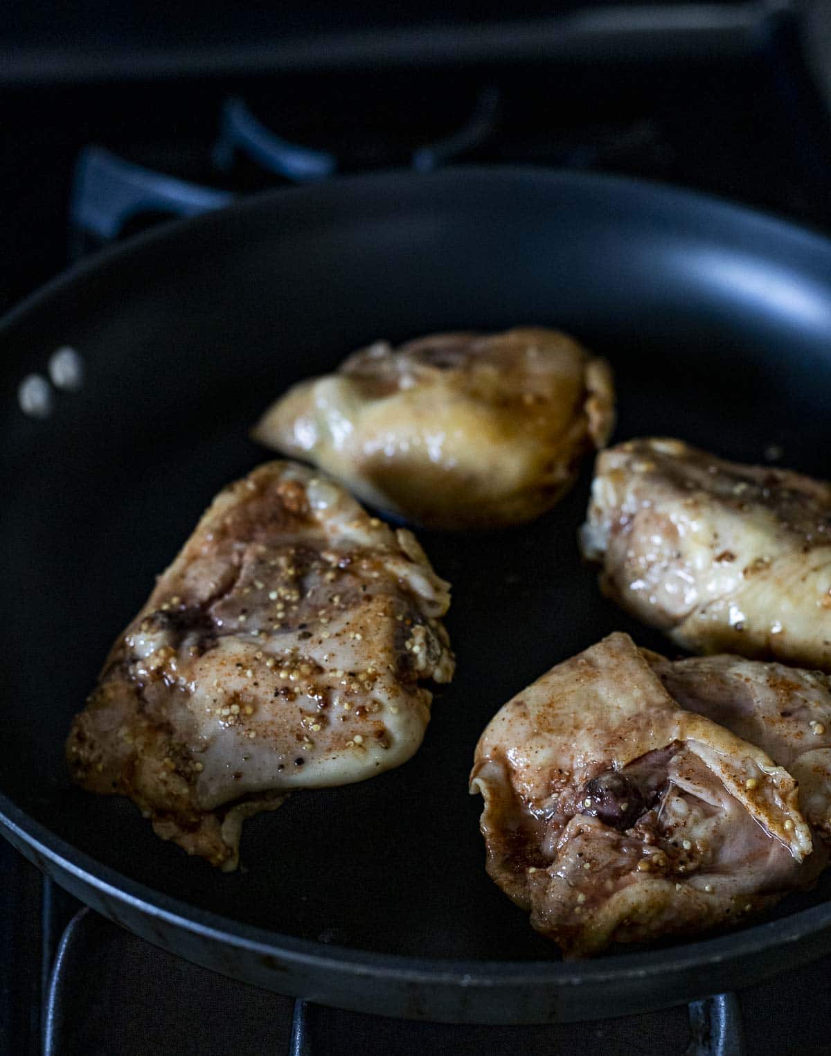 Chicken thighs being browned in a skillet.