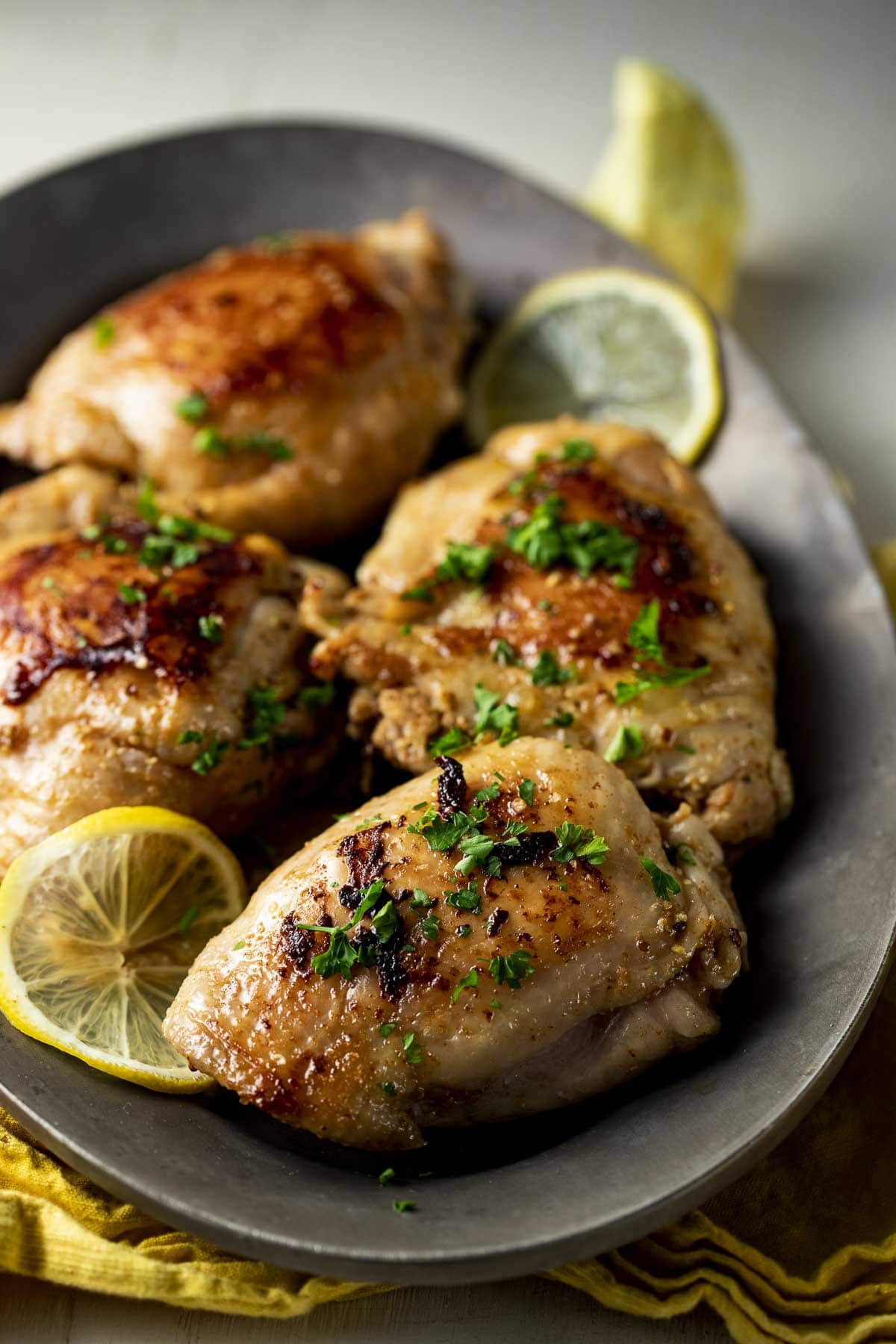 Sous vide chicken thighs served with chopped herbs and lemon slices.