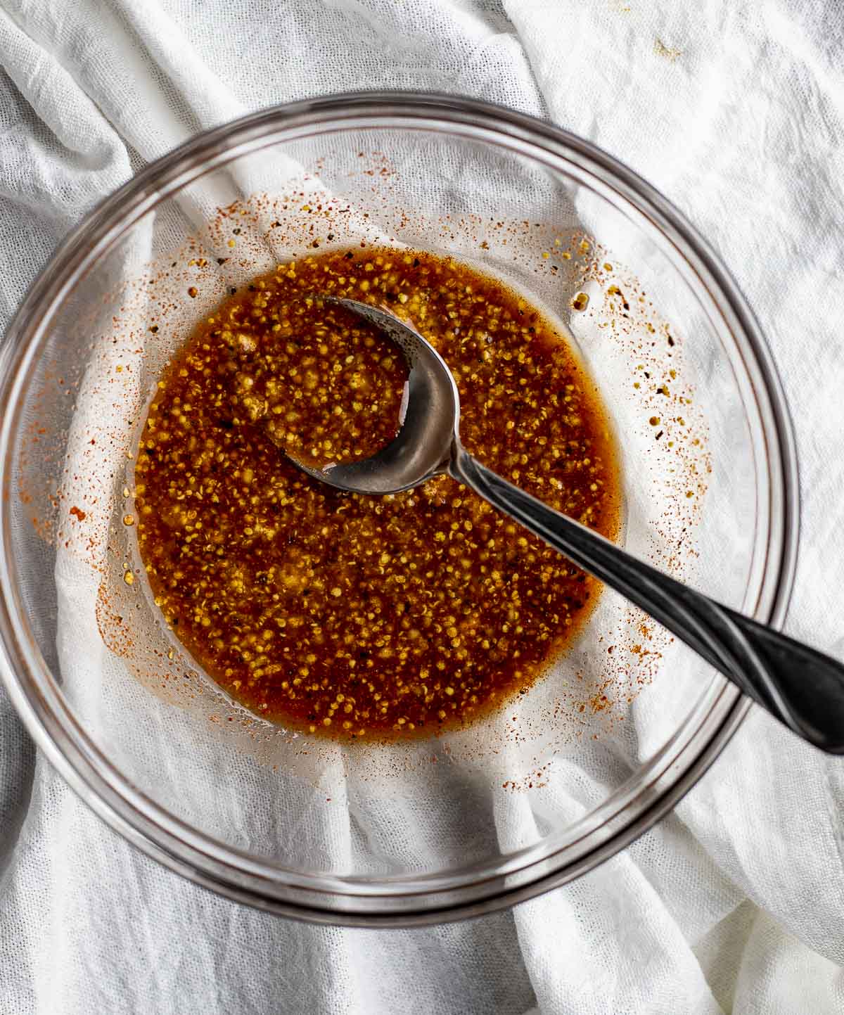Sauce ingredients stirred together in a glass bowl with a spoon.