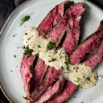 sliced beef on a plate with a white sauce
