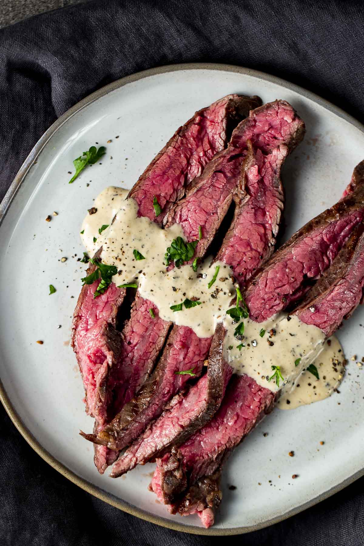 sliced beef on a plate with a white sauce