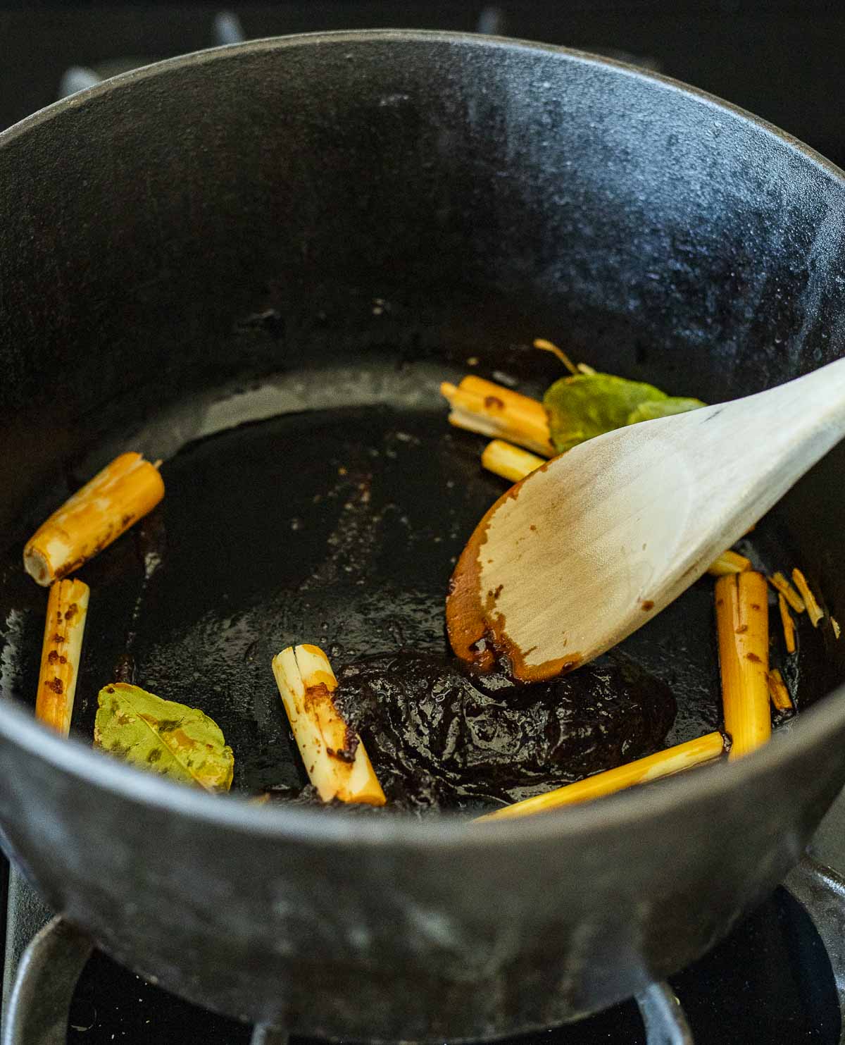 Lemongrass, ginger, kaffir lime leaves and nam prik pao sautéing in a pot.