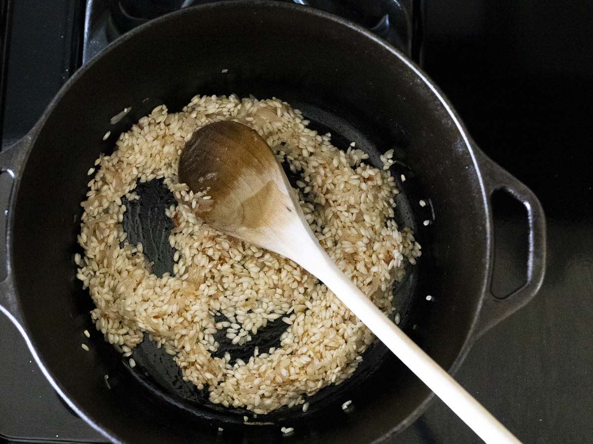 rice cooking in a large pot with a wooden spoon