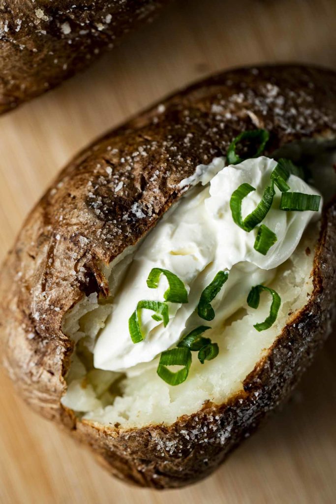baked potatoe with sour cream and chives in the middle
