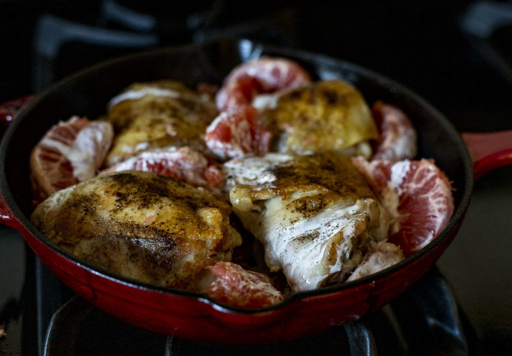 chicken thighs in a skillet with grapefruit slices