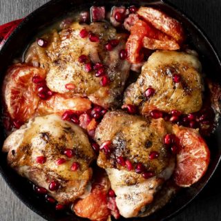 roasted chicken thighs, pomegranate seeds and grapefrut in a red skillet