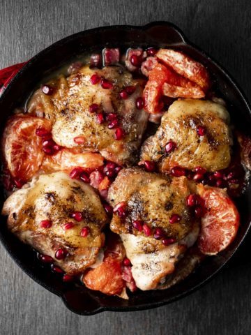 roasted chicken thighs, pomegranate seeds and grapefrut in a red skillet