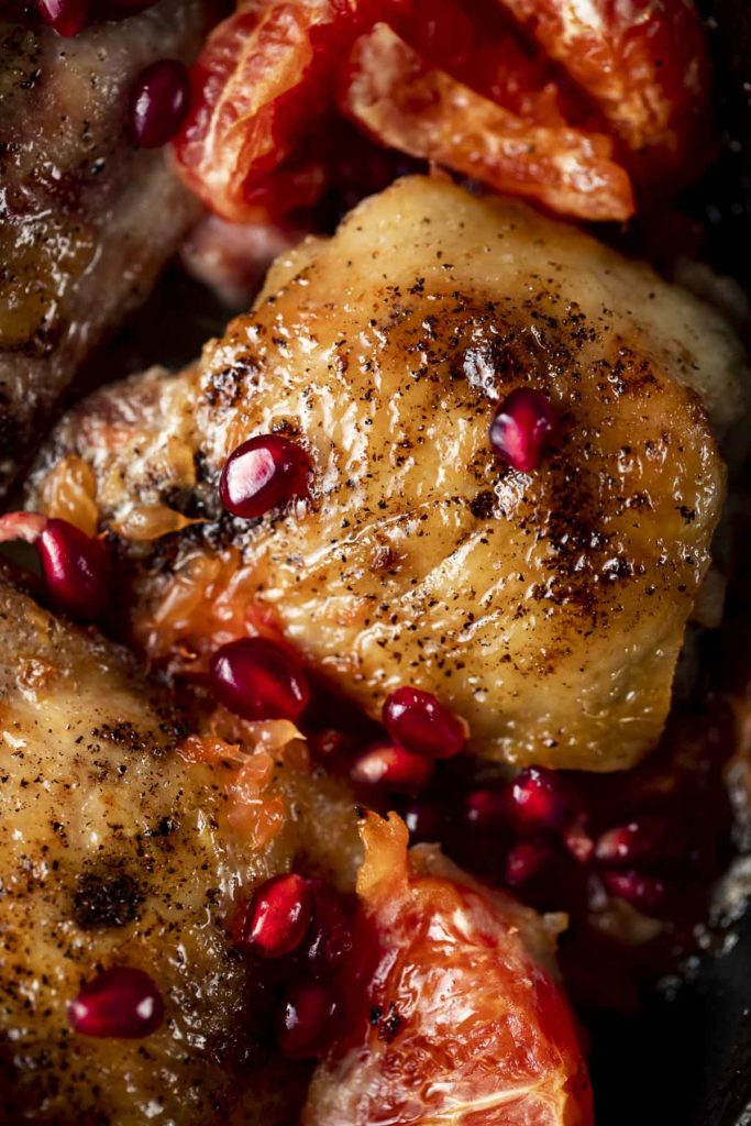 browned chicken thigh with pomegranate seeds on top
