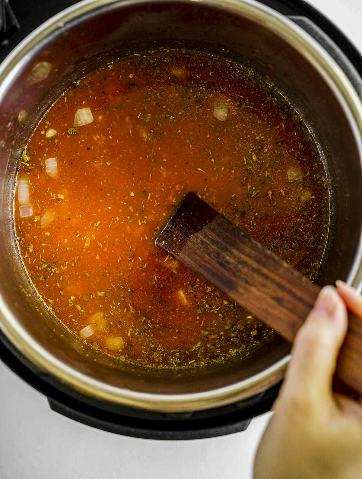Stirring the tomato soup ingredients inside of an Instant Pot.