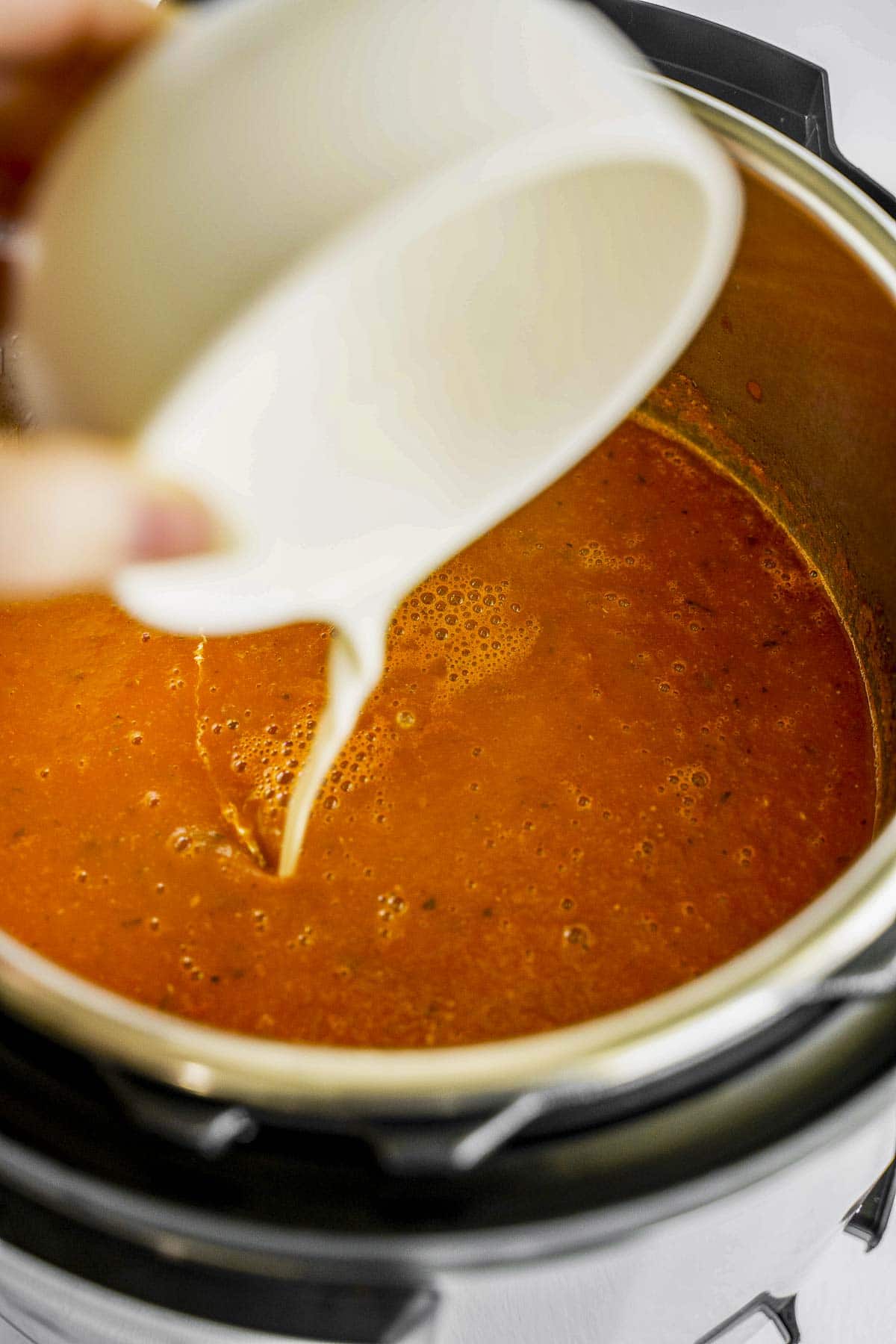 Adding in heavy cream to the Instant Pot tomato soup.