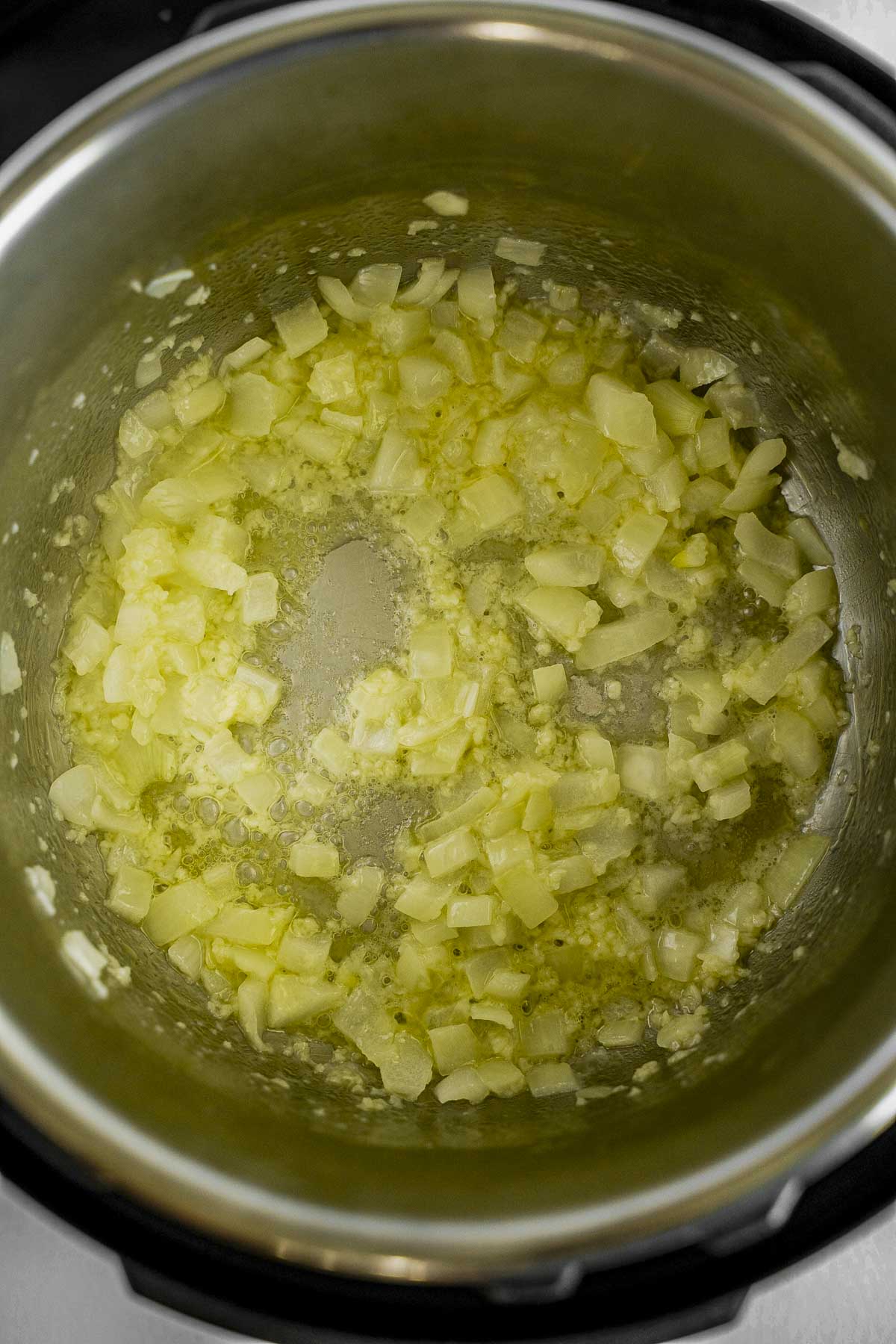 Instant pot with diced onions, melted butter, and olive oil.