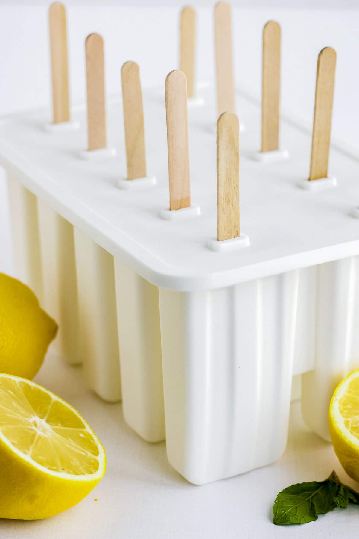 A white popsicle mold with lemons around it.