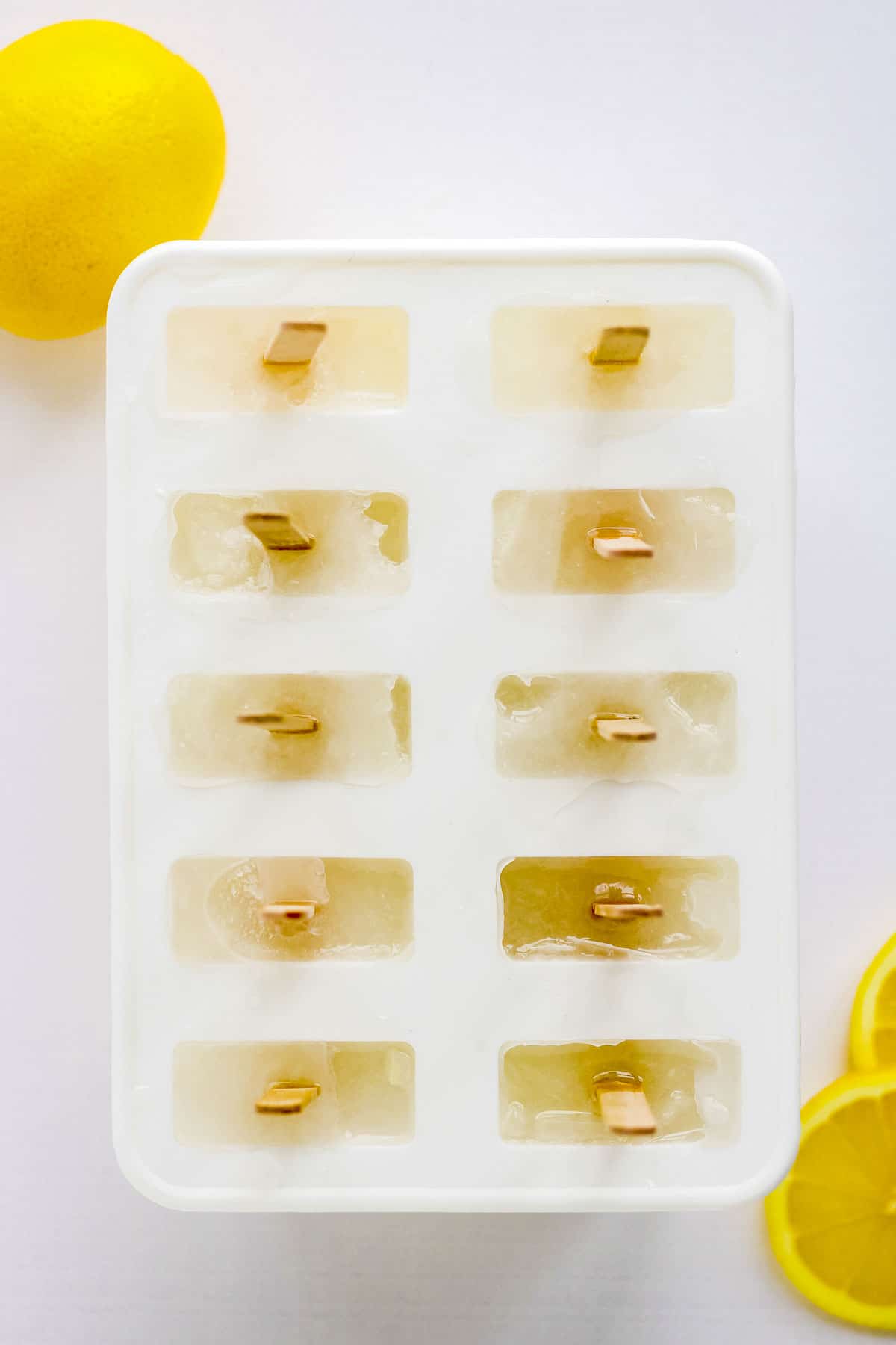 Overhead view of frozen lemonade popsicles in their molds.