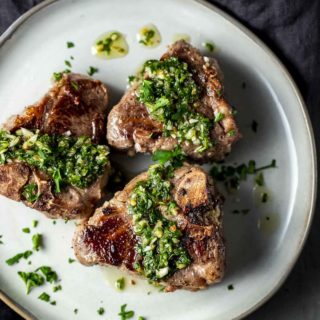 green chimichurri sauce drizzled over lamb chops on a plate