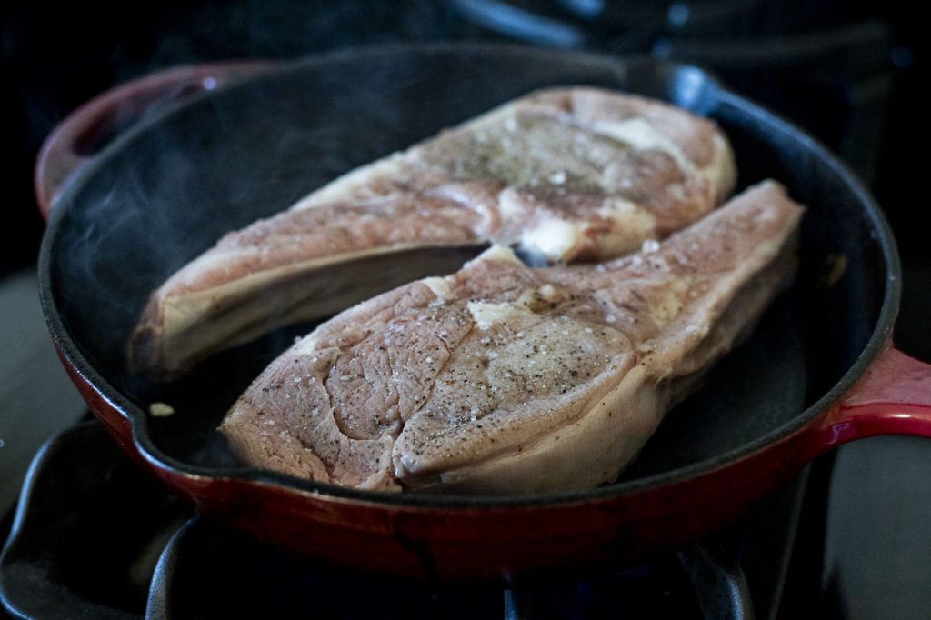 veal chops searing in a skillet