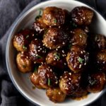 glazed meatballs with sesame seeds and green garnish